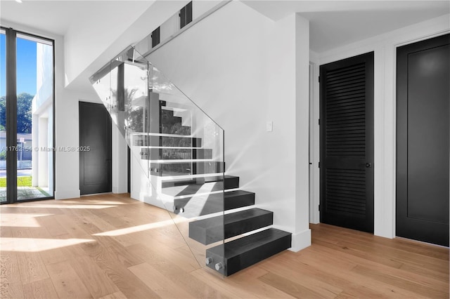 staircase featuring plenty of natural light, wood finished floors, and floor to ceiling windows