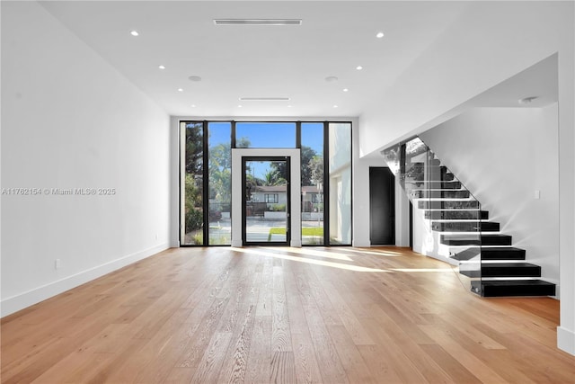 interior space with baseboards, stairway, expansive windows, recessed lighting, and wood finished floors