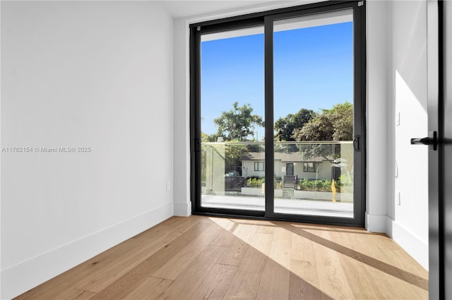 empty room with baseboards, wood-type flooring, and expansive windows