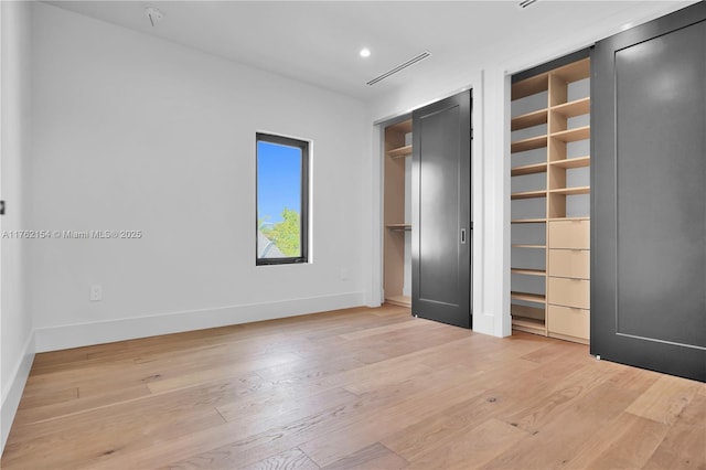 unfurnished bedroom with visible vents, two closets, baseboards, light wood-type flooring, and recessed lighting