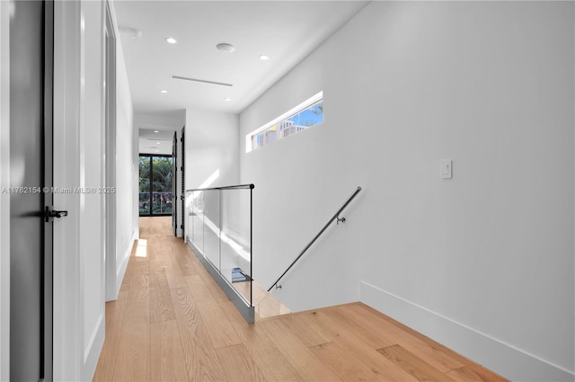 hallway with an upstairs landing, recessed lighting, baseboards, and light wood-style floors