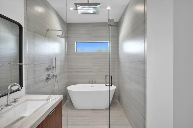 full bathroom with tile walls, a soaking tub, vanity, and a shower