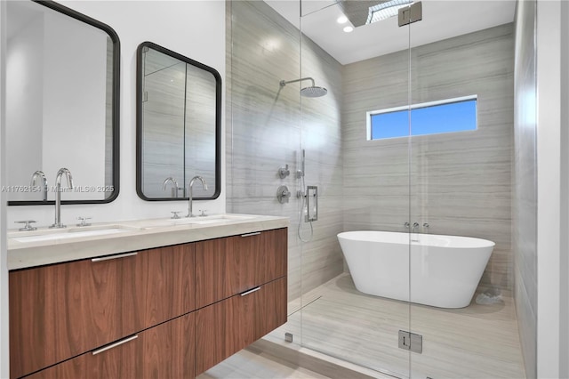 bathroom featuring double vanity, a stall shower, a freestanding tub, tile walls, and a sink