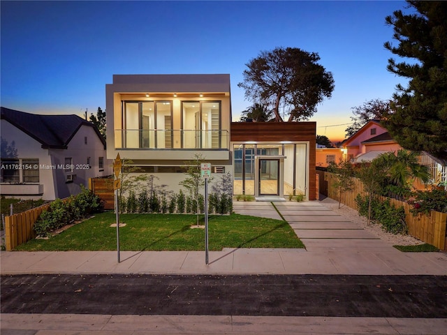 view of front of house with stucco siding, a front yard, and fence