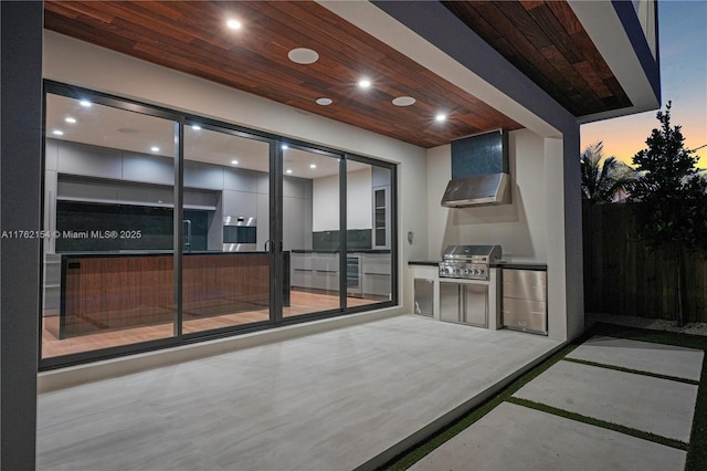 patio terrace at dusk featuring exterior kitchen and grilling area