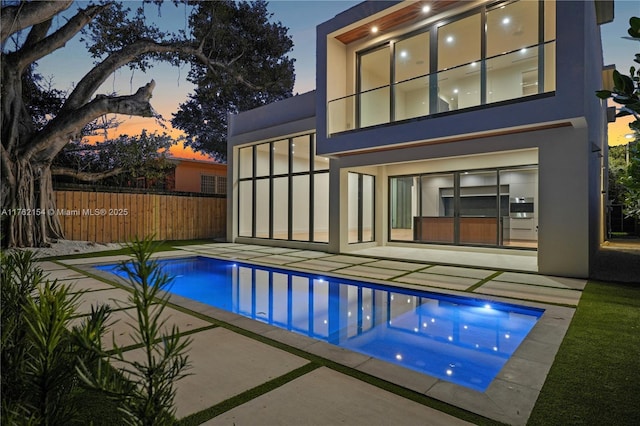 pool at dusk with a fenced in pool, a patio, and fence