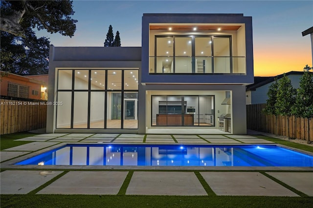 back of property featuring stucco siding, a patio, a fenced in pool, and fence