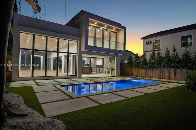 back of property with a patio area, stucco siding, a fenced in pool, and fence