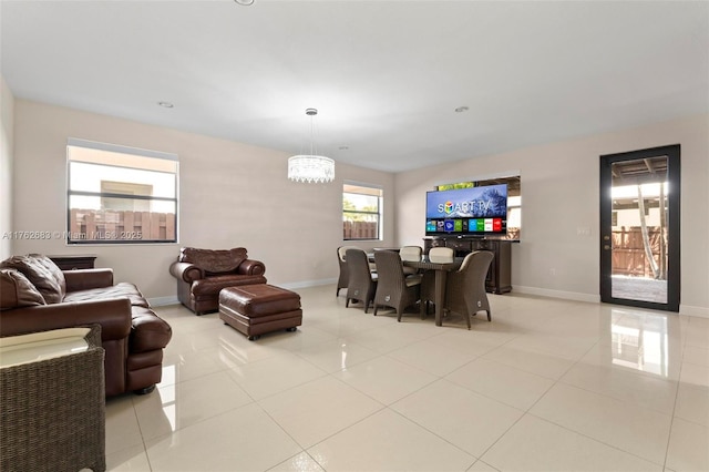 living room with light tile patterned floors, an inviting chandelier, and baseboards