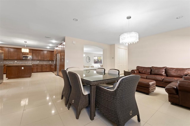 dining area featuring light tile patterned floors, arched walkways, and an inviting chandelier