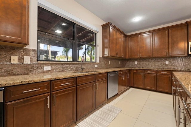 kitchen with backsplash, light stone countertops, light tile patterned flooring, stainless steel appliances, and a sink