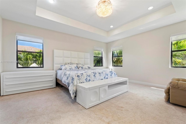 carpeted bedroom with multiple windows, baseboards, and a tray ceiling