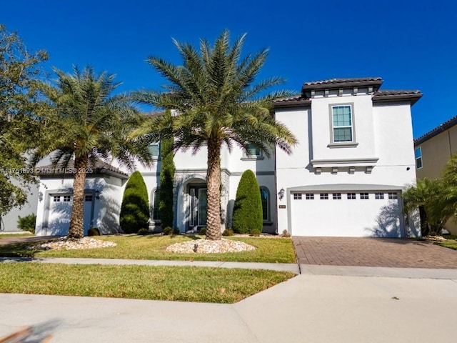 view of front of property with stucco siding, a tile roof, decorative driveway, a front yard, and an attached garage