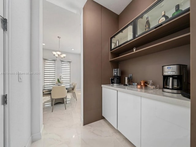 bar featuring baseboards, marble finish floor, and an inviting chandelier