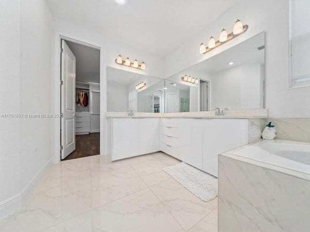 full bathroom featuring a walk in closet, marble finish floor, baseboards, a bath, and vanity