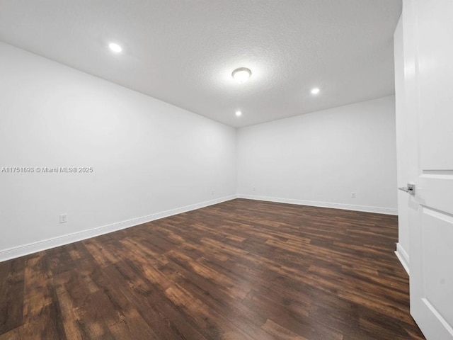 empty room with recessed lighting, baseboards, dark wood-type flooring, and a textured ceiling