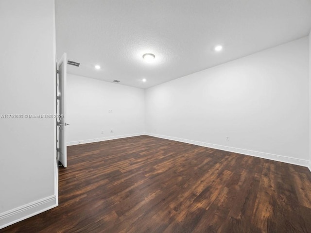 spare room featuring recessed lighting, visible vents, baseboards, and dark wood finished floors