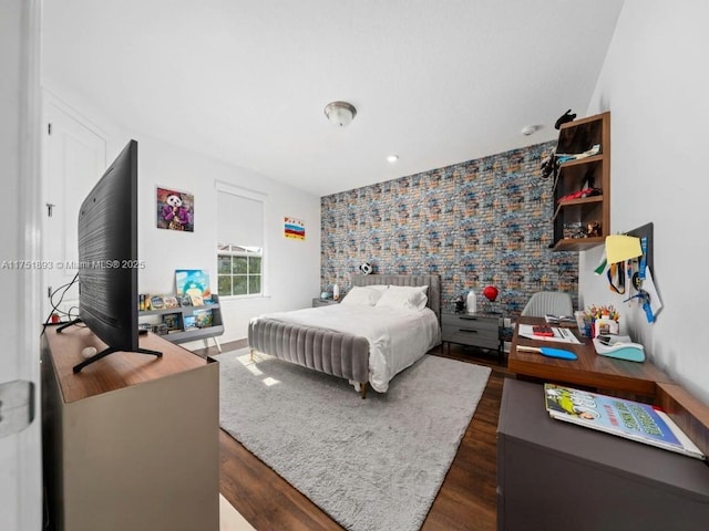 bedroom featuring dark wood-style floors and an accent wall