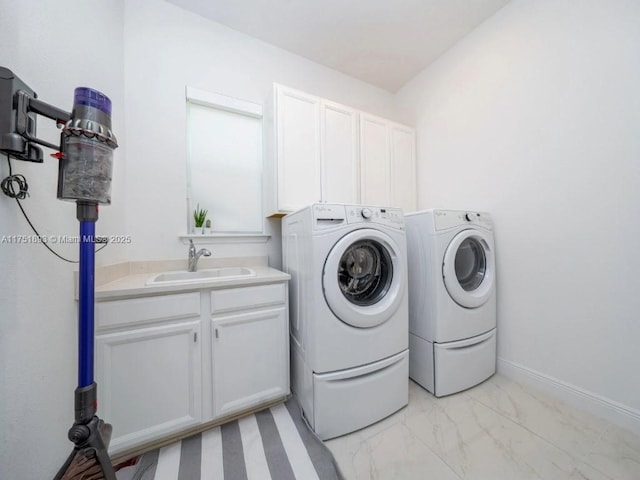 laundry room featuring marble finish floor, a sink, cabinet space, baseboards, and washing machine and clothes dryer