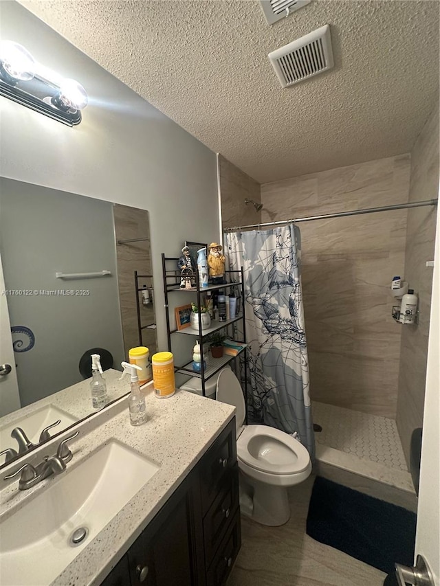 full bath featuring visible vents, tiled shower, a textured ceiling, and vanity