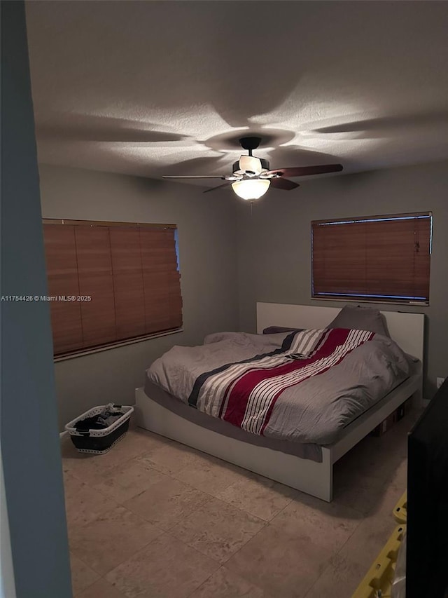 bedroom with a textured ceiling and a ceiling fan