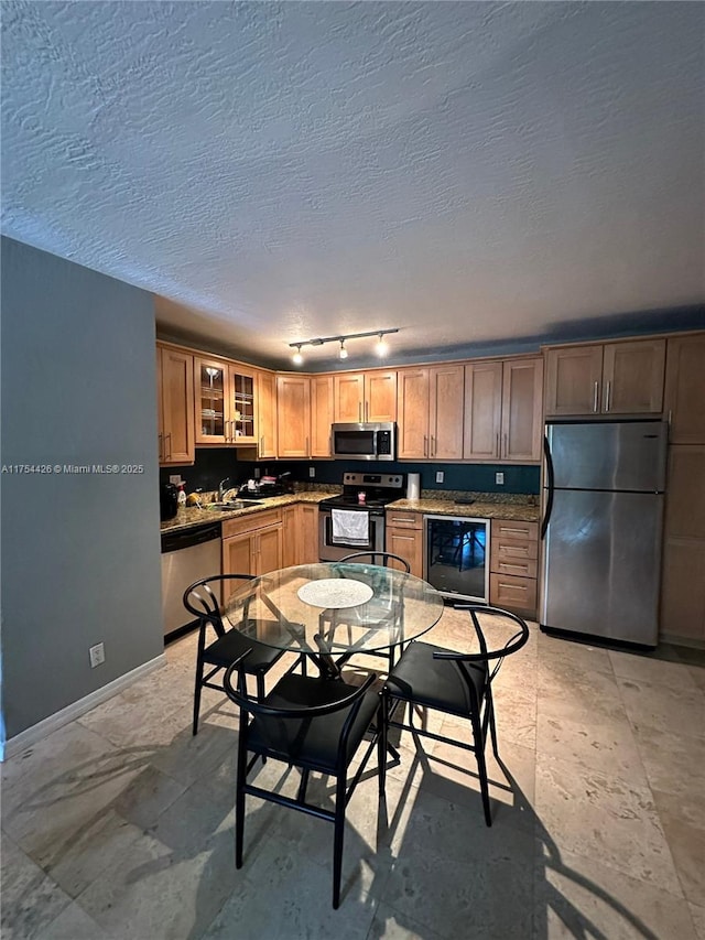 530 NE 15th Ct Unit 1, Fort Lauderdale, FL 33304 - kitchen featuring appliances with stainless steel finishes, wine cooler, track lighting, glass insert cabinets, and a textured ceiling