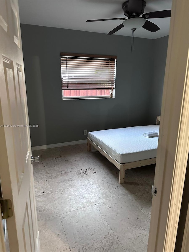 unfurnished bedroom with a ceiling fan and baseboards