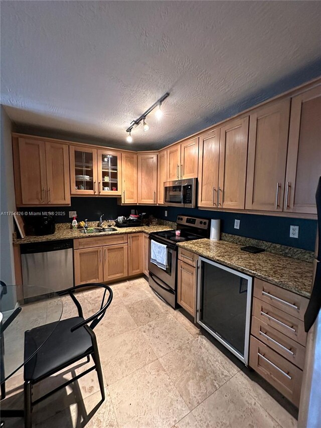 530 NE 15th Ct Unit 1, Fort Lauderdale, FL 33304 - kitchen featuring stainless steel appliances, glass insert cabinets, track lighting, a textured ceiling, and dark stone countertops