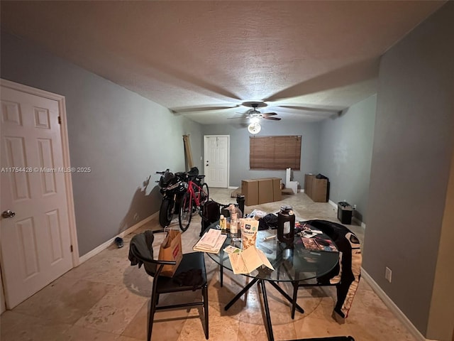 dining room featuring baseboards, a textured ceiling, and a ceiling fan