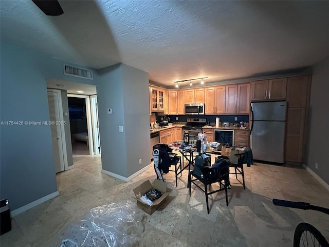 kitchen with visible vents, glass insert cabinets, baseboards, stainless steel appliances, and a textured ceiling