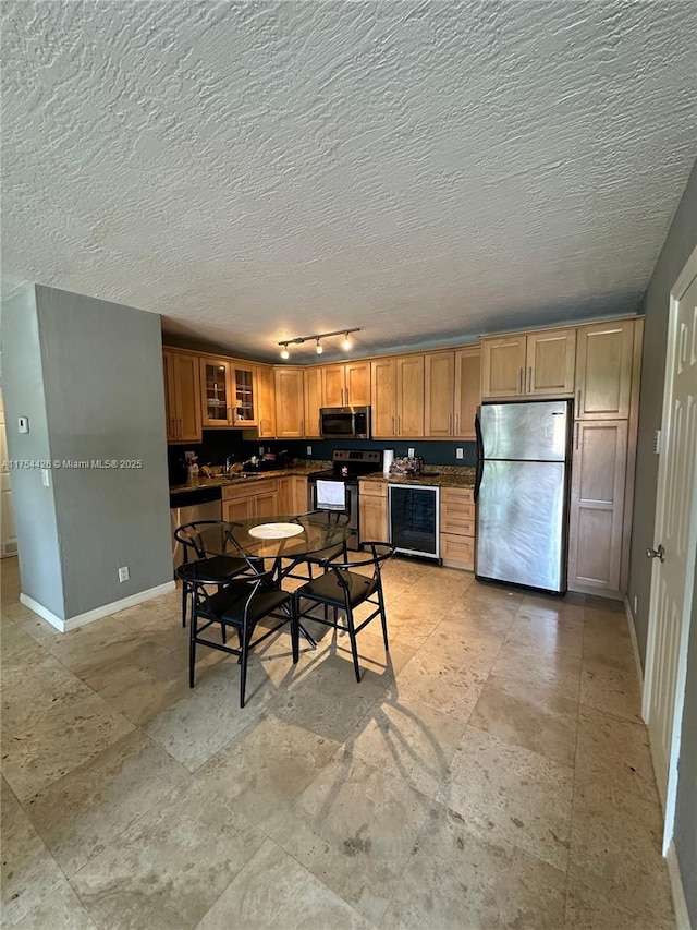 530 NE 15th Ct Unit 1, Fort Lauderdale, FL 33304 - kitchen with stainless steel appliances, wine cooler, track lighting, dark countertops, and glass insert cabinets