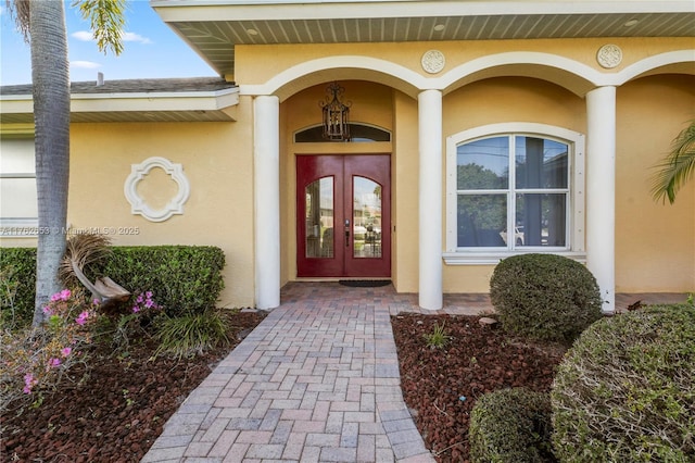 doorway to property featuring stucco siding, french doors, and a shingled roof