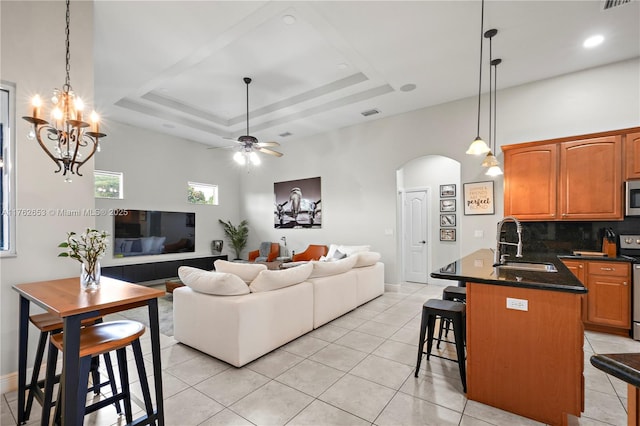 living area with light tile patterned floors, arched walkways, a raised ceiling, and ceiling fan