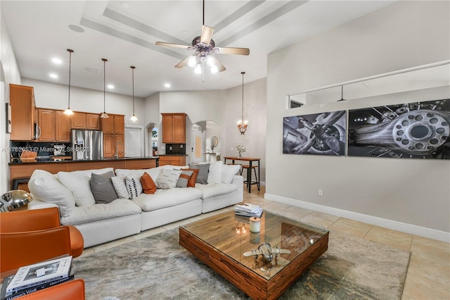 living area featuring ceiling fan, baseboards, arched walkways, and light tile patterned flooring