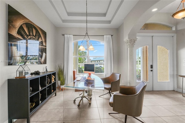 office space with a wealth of natural light, a tray ceiling, arched walkways, and light tile patterned flooring