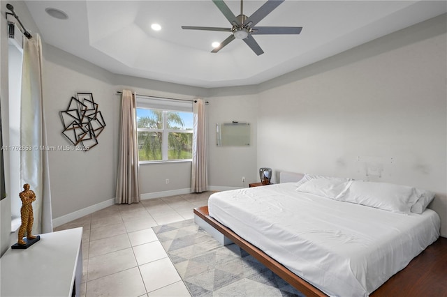 bedroom featuring baseboards, ceiling fan, a tray ceiling, light tile patterned floors, and recessed lighting