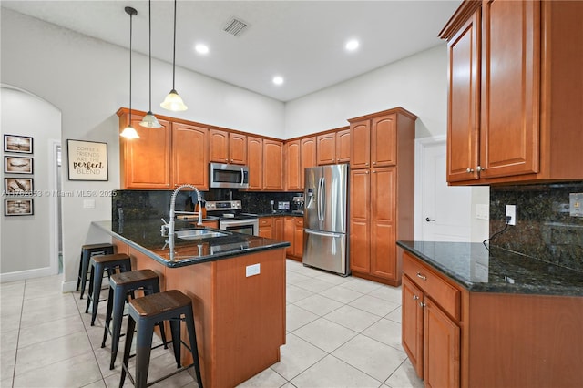 kitchen featuring visible vents, appliances with stainless steel finishes, a kitchen breakfast bar, a peninsula, and a sink