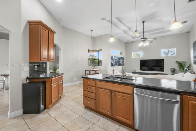 kitchen with a sink, arched walkways, brown cabinetry, a raised ceiling, and dishwasher