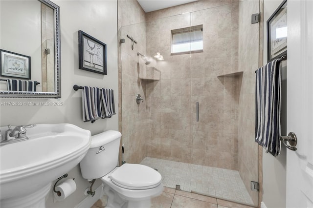 bathroom featuring tile patterned flooring, toilet, a stall shower, and a sink