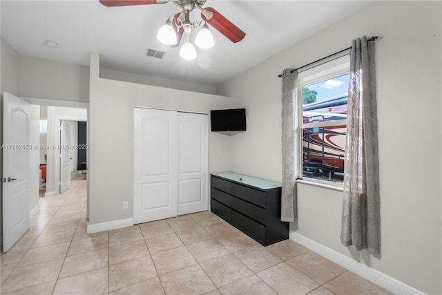 bedroom with light tile patterned floors, visible vents, a closet, and baseboards