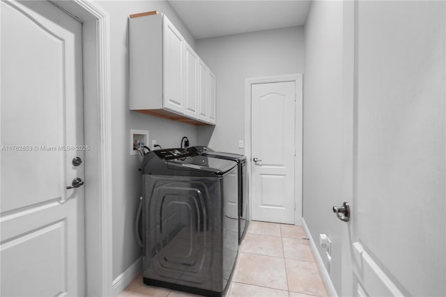 clothes washing area featuring washer and dryer, baseboards, cabinet space, and light tile patterned flooring