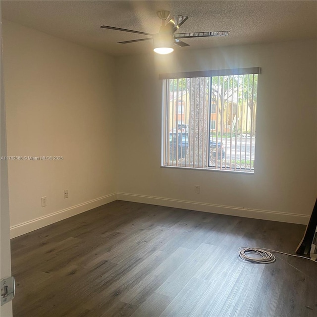 unfurnished room featuring dark wood finished floors, ceiling fan, a textured ceiling, and baseboards