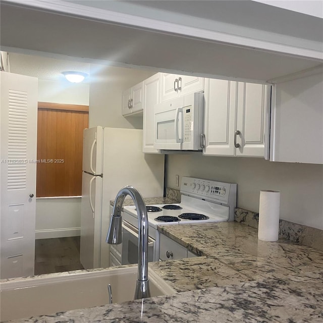 kitchen featuring white appliances, light stone counters, a sink, dark wood-type flooring, and white cabinetry