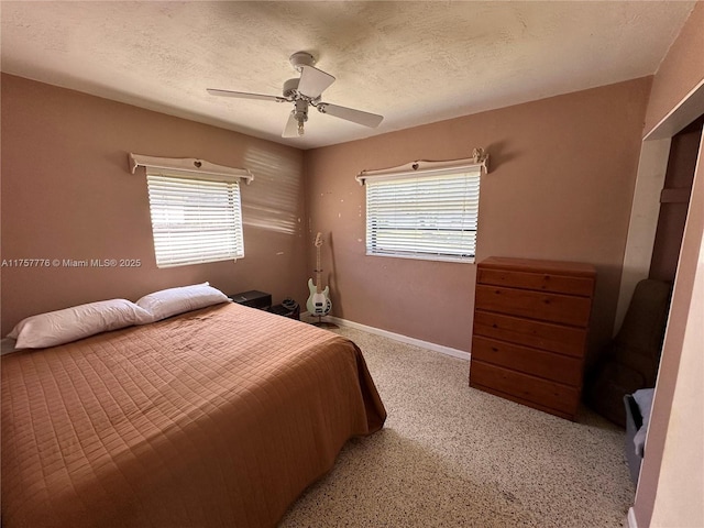 bedroom featuring multiple windows, a ceiling fan, baseboards, and a textured ceiling