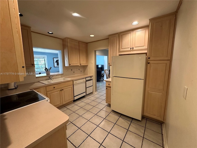 kitchen featuring light brown cabinetry, light countertops, light tile patterned flooring, white appliances, and a sink