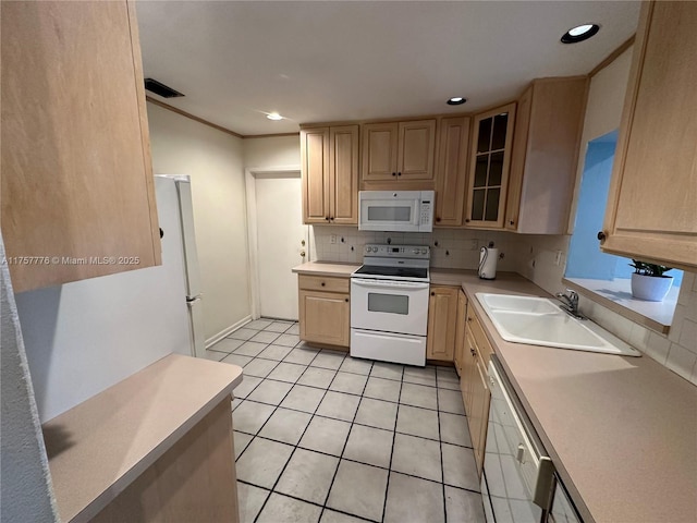 kitchen featuring light brown cabinetry, a sink, backsplash, white appliances, and light countertops