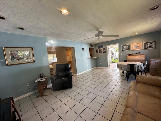 living room featuring ceiling fan, baseboards, a textured ceiling, and light tile patterned flooring