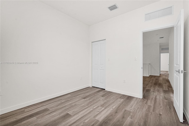 spare room featuring wood finished floors, visible vents, and baseboards