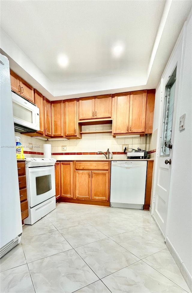 kitchen with white appliances, backsplash, and brown cabinetry