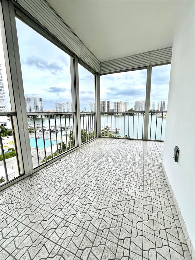 unfurnished sunroom featuring a view of city, a healthy amount of sunlight, and a water view